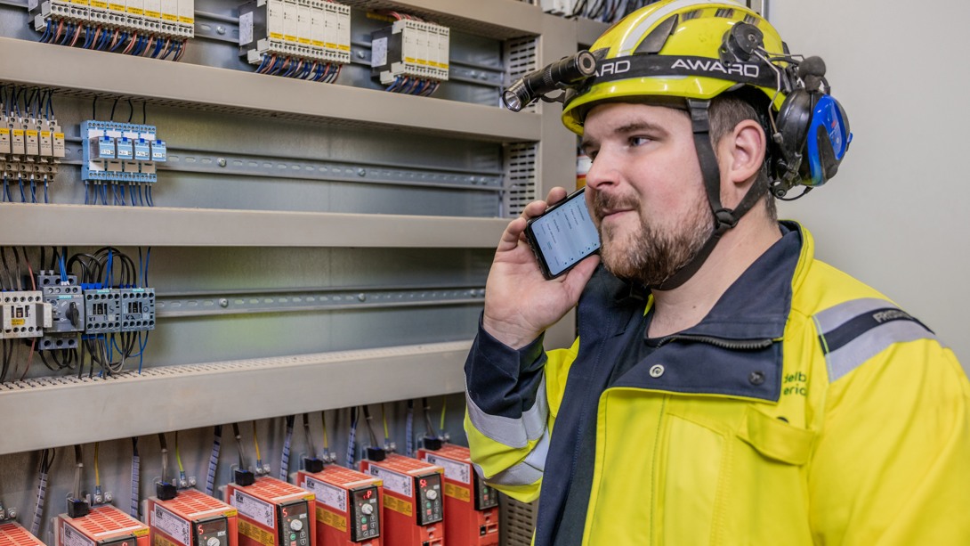 En person pratar i telefon bredvid ett elskåp.