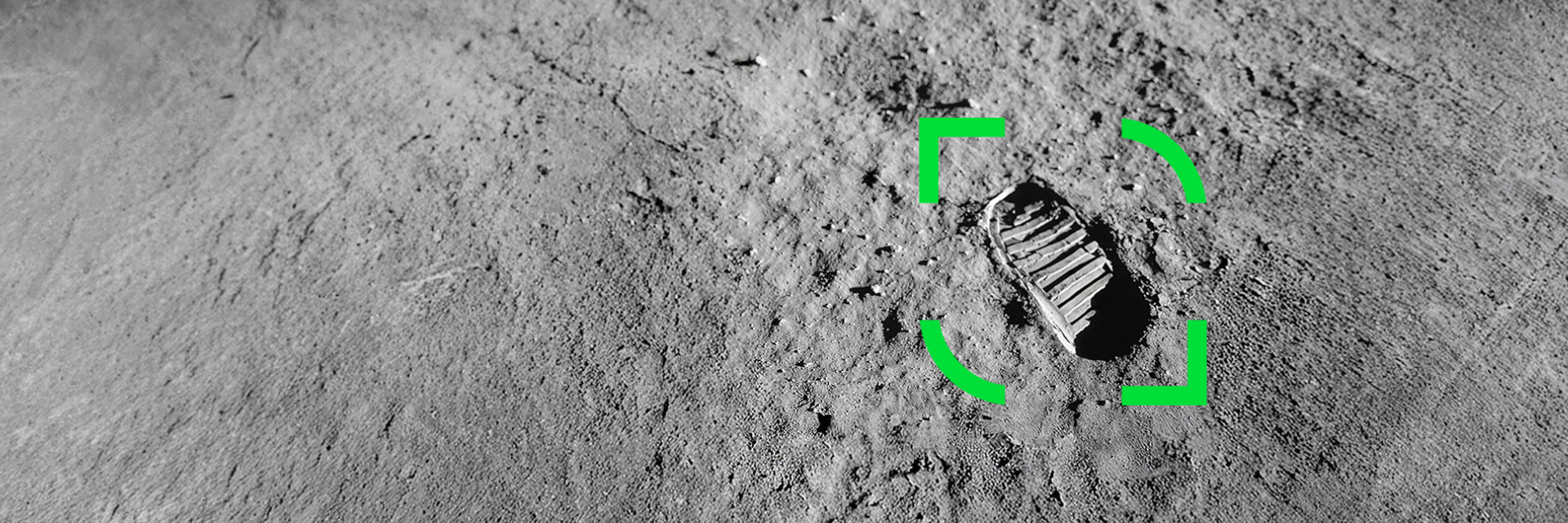 Fotavtryck i månens yta med ett grönt markeringsfokus runt avtrycket, omgiven av grå, kornig terräng.