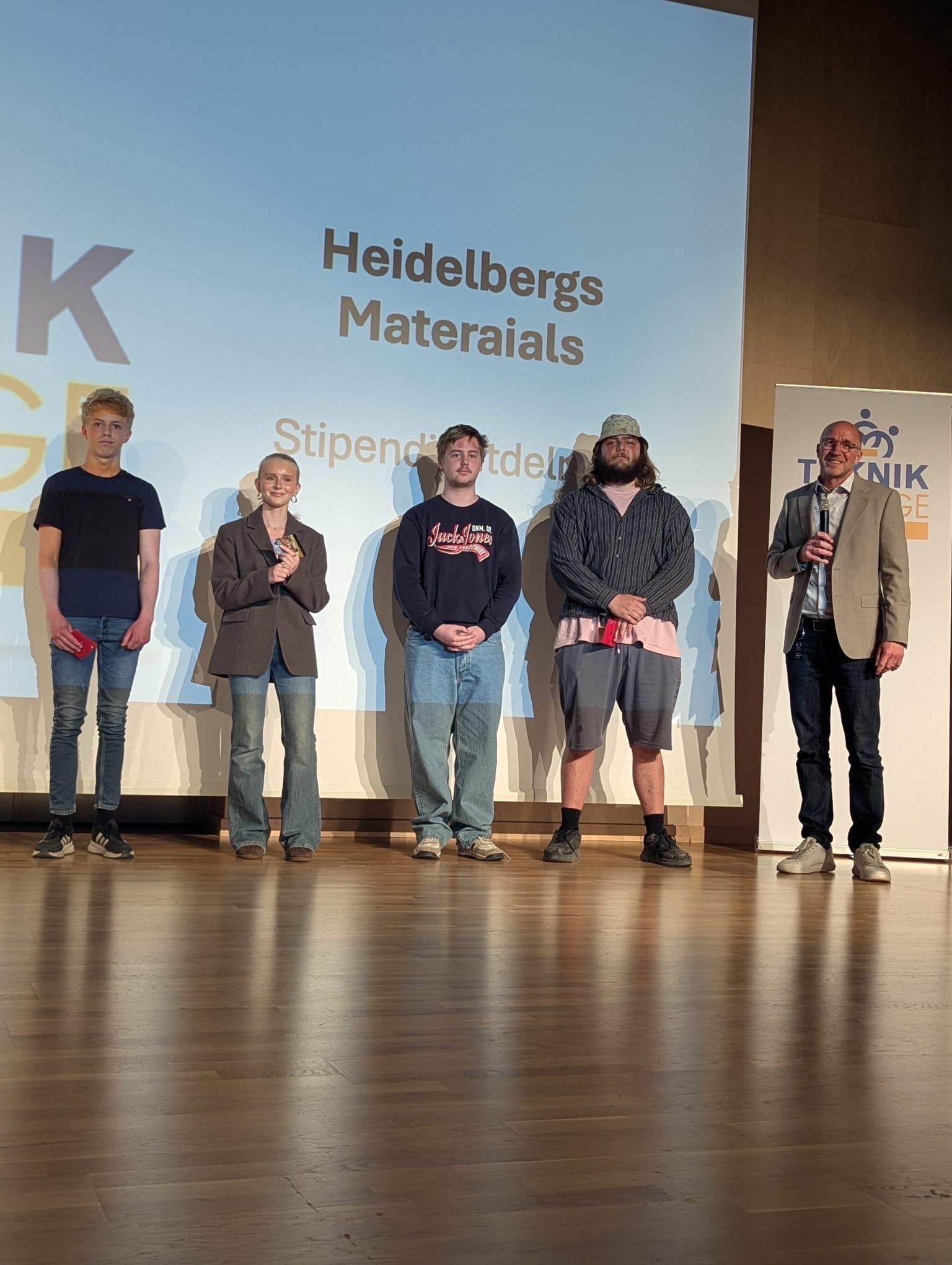 Fem personer står på en scen vid ett evenemang i Slite med Heidelberg Materials i fokus.