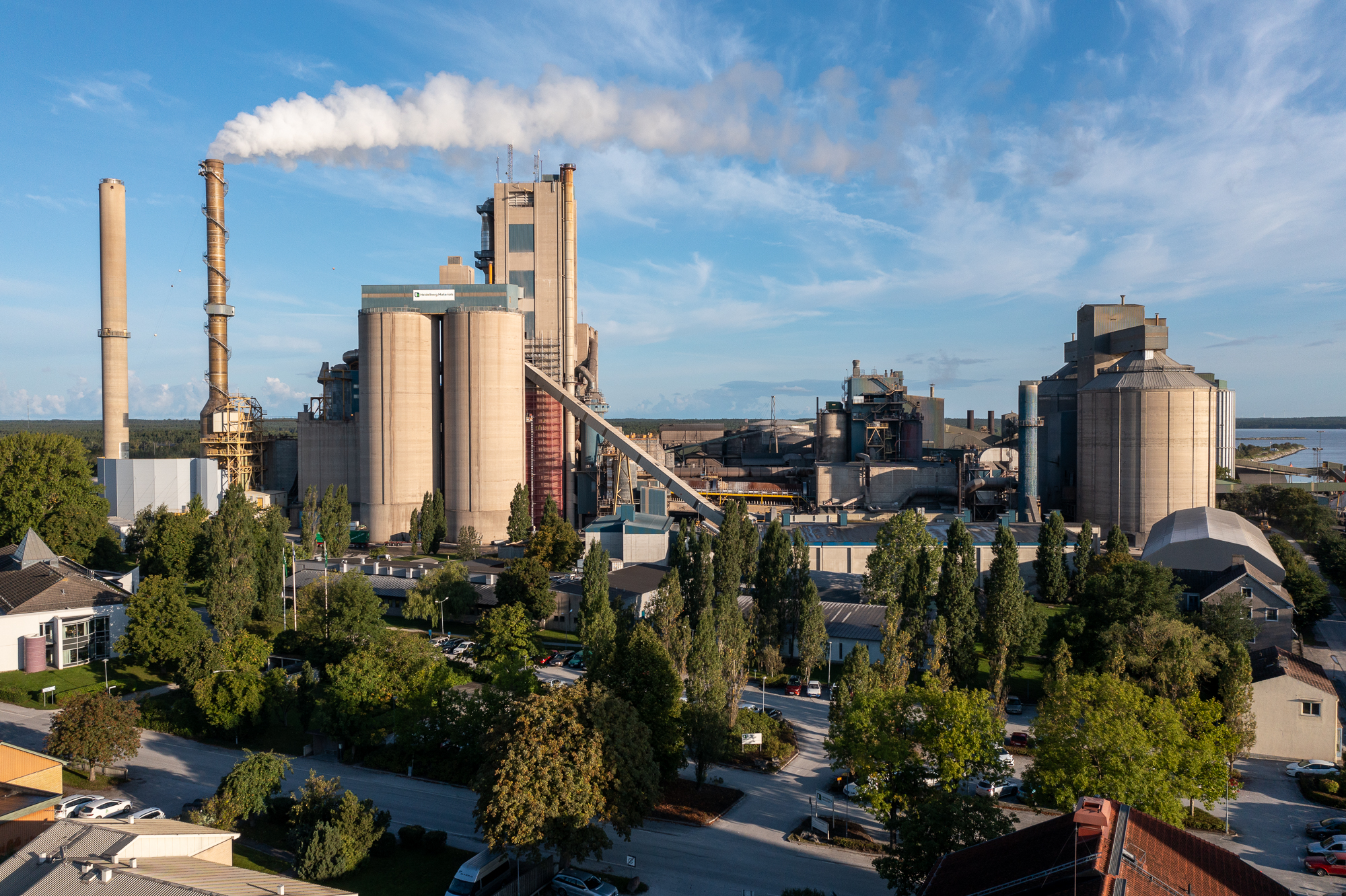 Cementfabriken i Slite med skorstenar och ånga som stiger mot en blå himmel.