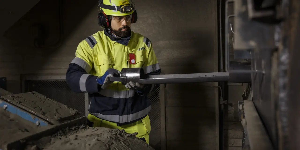 Medarbetare står vid en maskin i cementfabriken i Slite