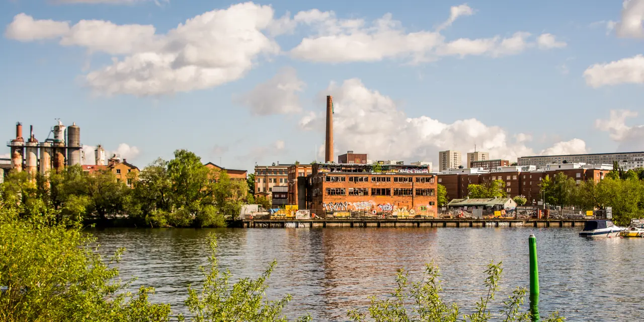 En industribyggnad vid Lövholmen, Stockholm omgiven av grönska och andra byggnader.