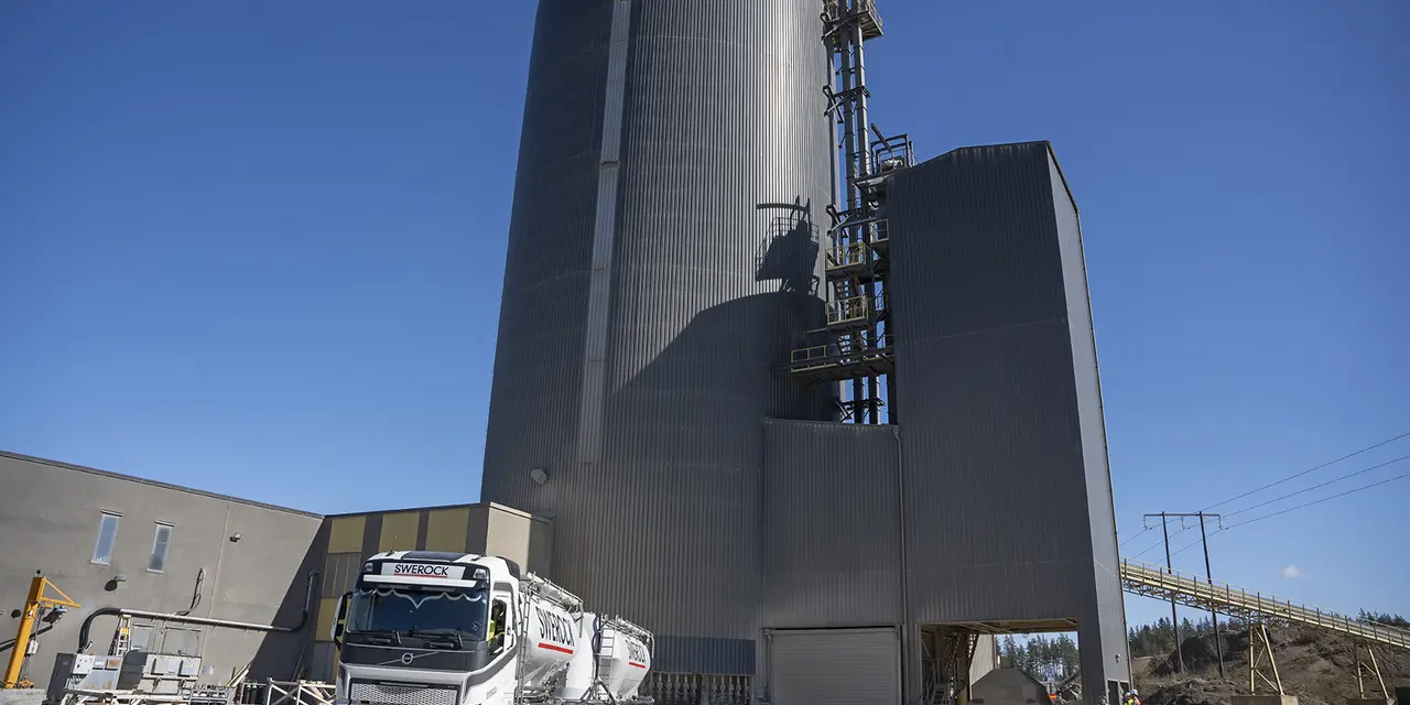 En industribyggnad med höga silotorn och en lastbil parkerad framför.