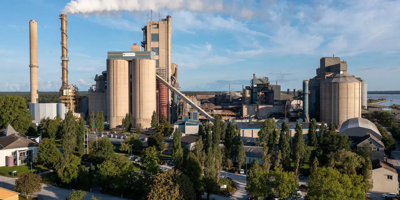 Cementfabriken i Slite med skorstenar och ånga som stiger mot en blå himmel.