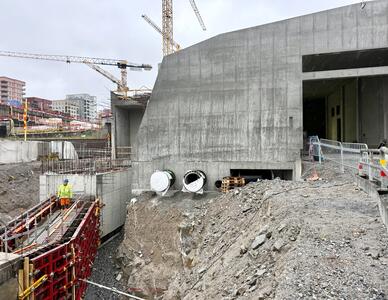 Betongbyggnad på en byggarbetsplats med kranar i bakgrunden.